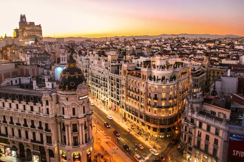 Vista aérea de la Gran Vía de Madrid al atardecer, entre edificios históricos
